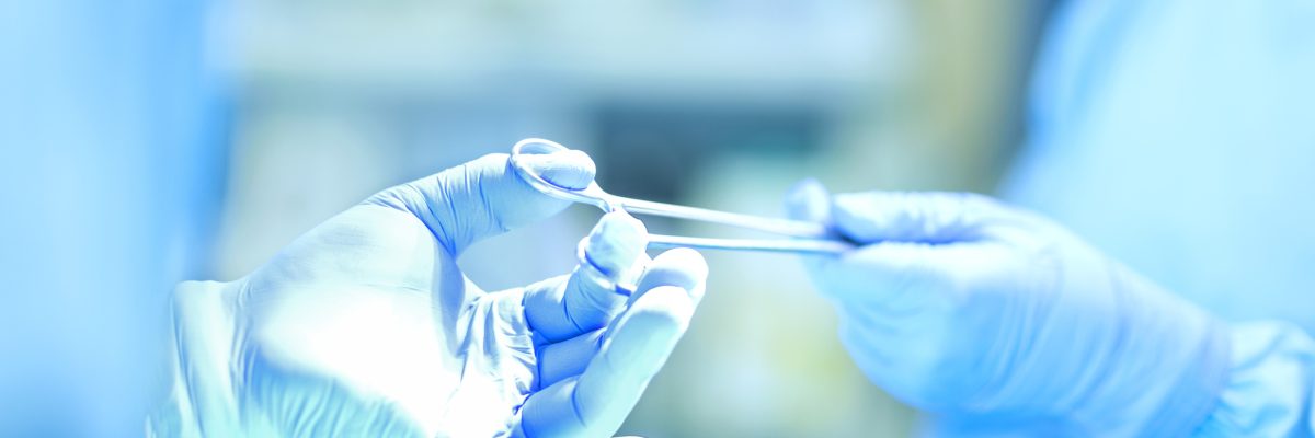 Cropped image of surgeon giving scissors to colleague during surgery in operating room. Horizontal shot.